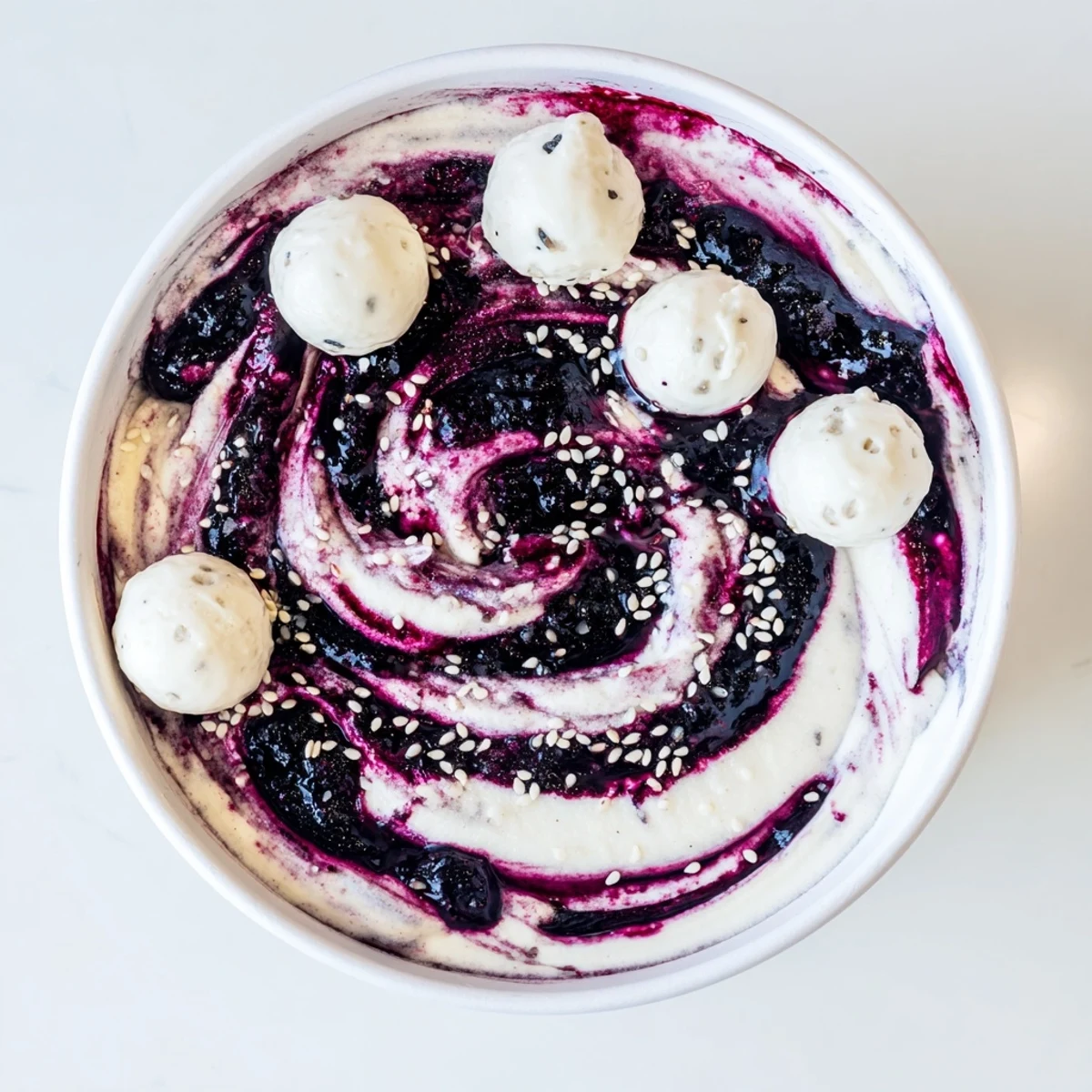A Galaxy Spiral dessert shows a berry jam swirl atop creamy yogurt, speckled with star-like goat cheese.