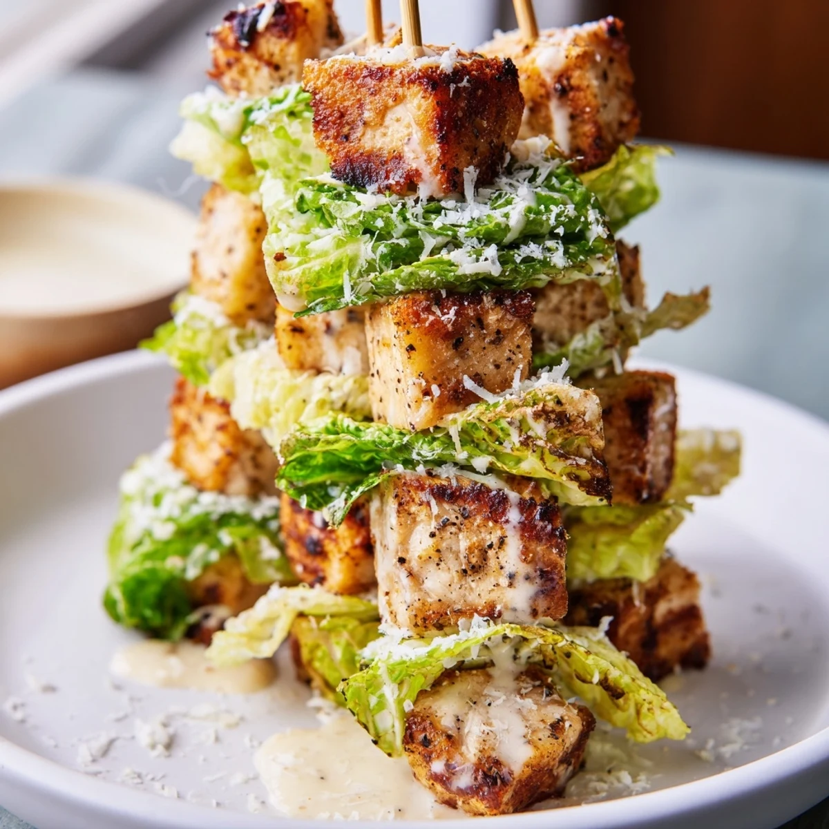 Chicken Caesar Salad Skewers arranged on a platter with vibrant green romaine and golden croutons, ideal appetizer.