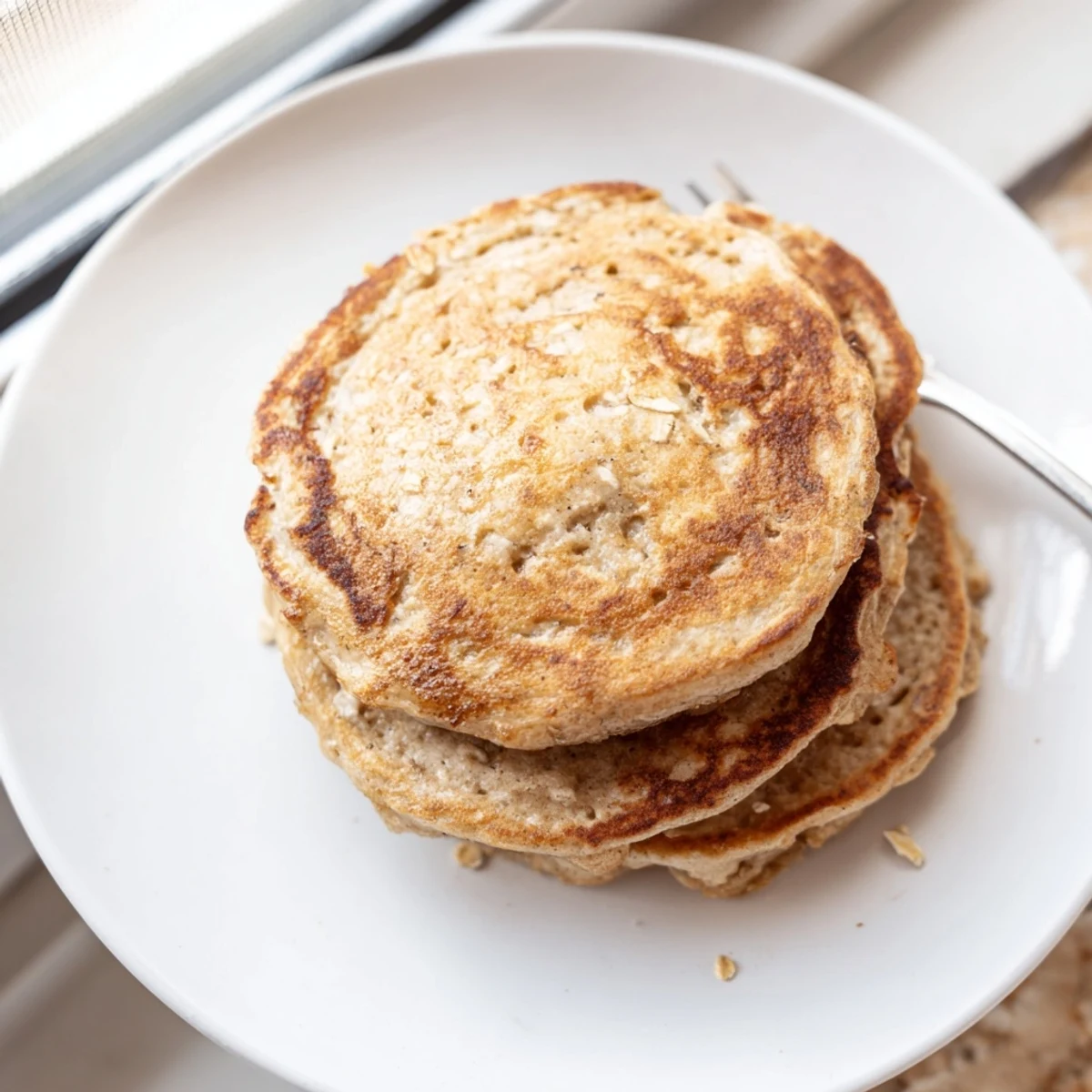 Golden-brown banana oat pancakes stacked high, ready to be drizzled with maple syrup.