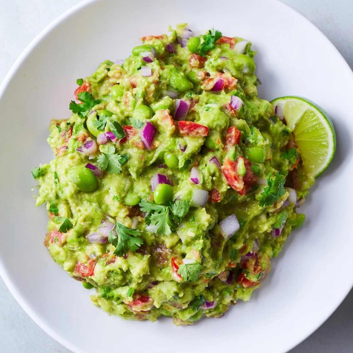 Creamy edamame guacamole, a vibrant green dip ready to be scooped with tortilla chips.