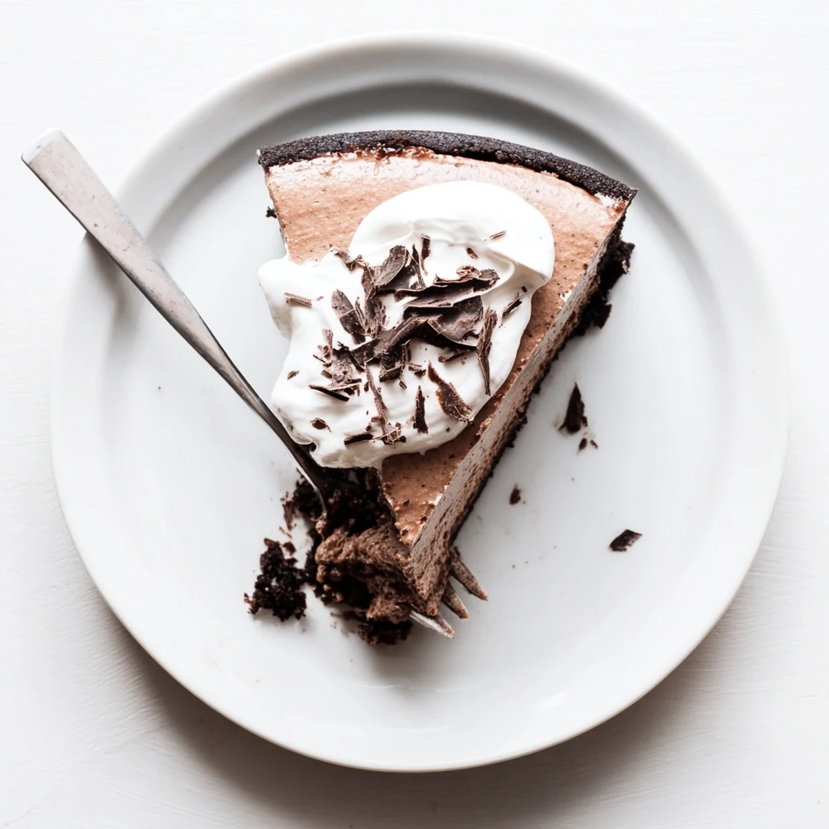 A slice of rich, fudgy Lighter Chocolate Cottage Cheese Cheesecake sits on a white plate with a fork, ready to enjoy.