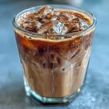 Iced brown sugar oat milk shaken espresso with frothy espresso and cinnamon in a tall glass over ice.