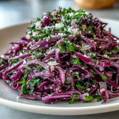 Freshly shredded Red Cabbage Coleslaw With Apple and Parmesan tossed in a tangy vinaigrette in a white ceramic bowl.