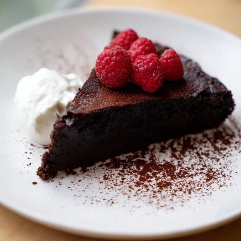 This flourless chocolate cake looks incredibly rich, ready to serve with fresh berries and whipped cream.