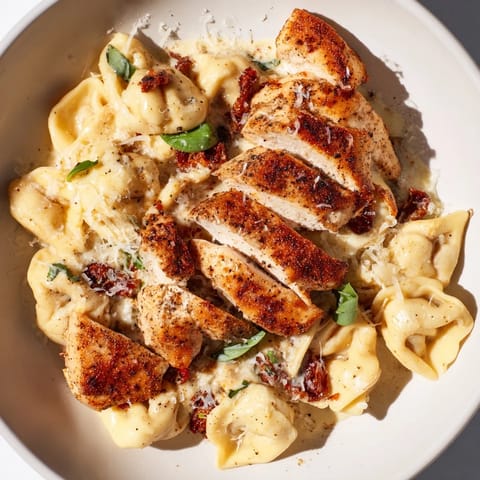 A steaming bowl of Marry Me Chicken Tortellini shows off its rich, sun-dried tomato and basil garnish.