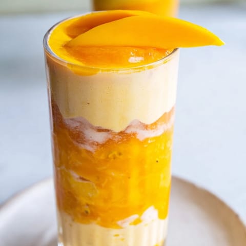 Cool, layered Tropical Sunset Smoothie with mango, passion fruit, and orange juice, ready to serve.