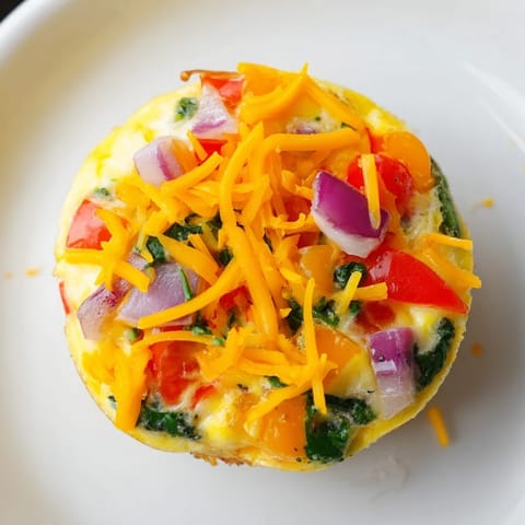 Freshly baked Customizable Egg Muffins filled with savory cheese and bright peppers served on a plate.