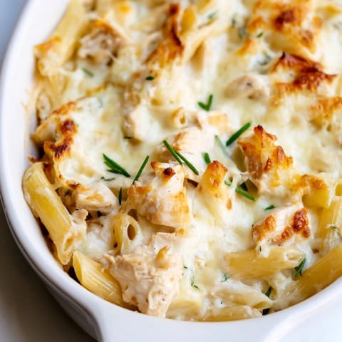 A spoon serves up creamy Chicken Ranch Pasta Bake, revealing tender chicken and penne coated in ranch sauce.
