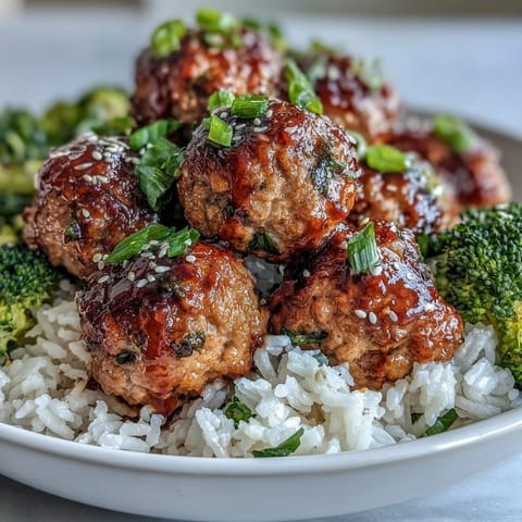 Juicy turkey meatballs simmer in sweet garlic glaze over rice and blanched broccoli, served in a ceramic bowl for a wholesome meal.