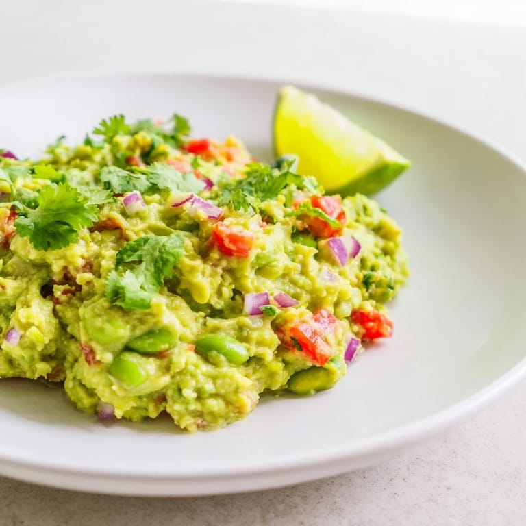 A bowl overflowing with fresh edamame guacamole, perfect as an appetizer for your next gathering.