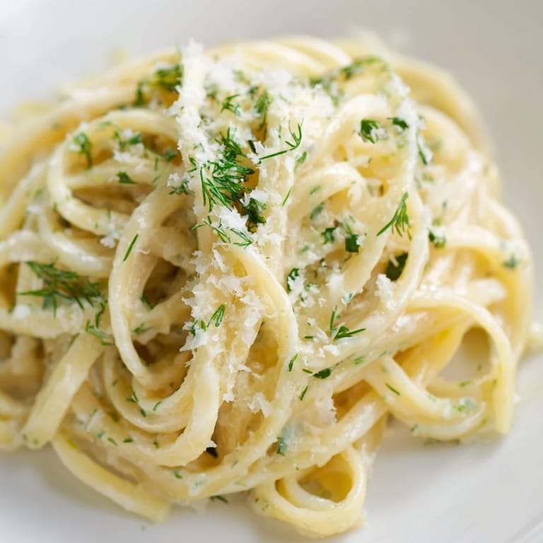 A close-up view of steaming Creamy Dill Pasta; the creamy sauce clings perfectly to each strand.