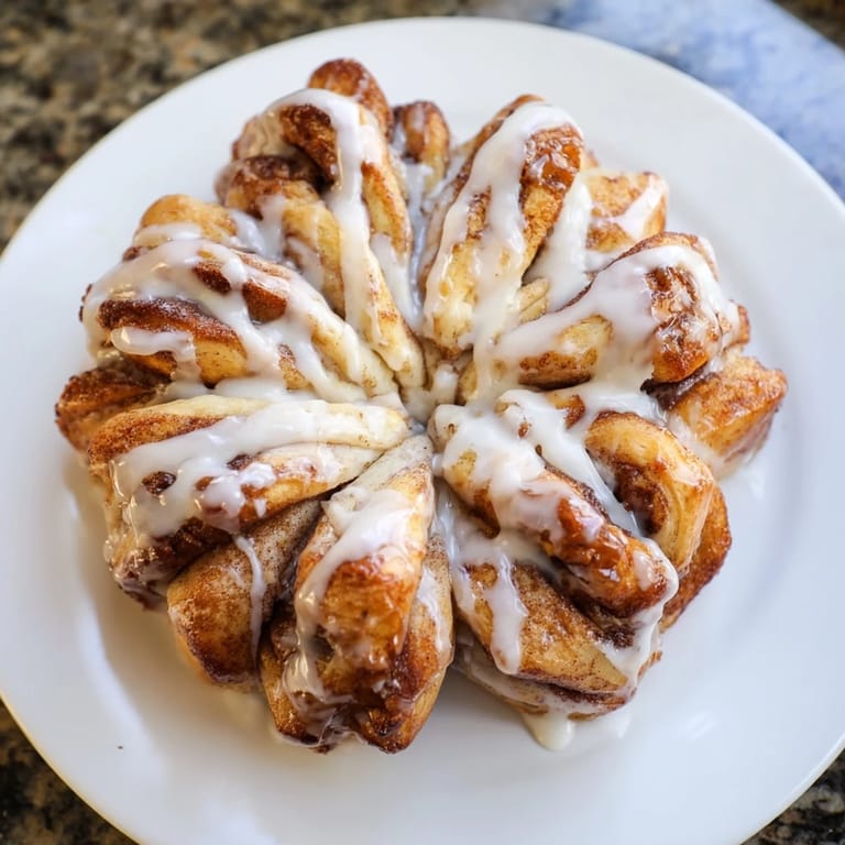 A close-up of a delightful Cinnamon Roll Pull-Apart Snowflake with a generous drizzle of sweet, creamy icing.