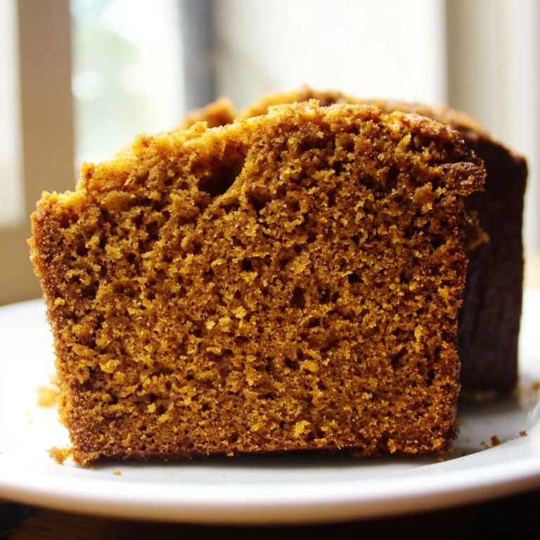 Golden pumpkin bread loaf cooling on a wire rack, with rich orange crumb and optional walnut pieces scattered on top.
