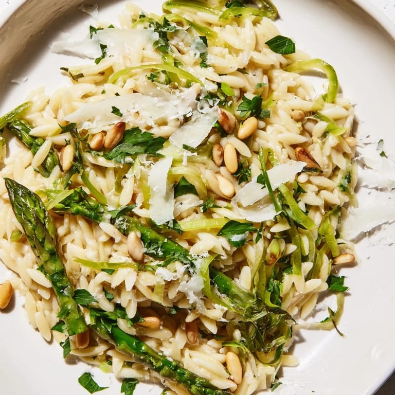 A close-up view of the vibrant Mediterranean Asparagus Lemon Orzo Salad, featuring shiny pasta, green veggies, and a zesty dressing.