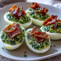 Green Eggs and Ham Deviled Eggs with Spinach Filling: vibrant, creamy spinach yolk filling in classic egg whites, topped with crispy ham crumbles for a fun twist.