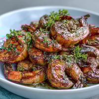 A vibrant bowl of lemon garlic shrimp over brown rice with fresh vegetables and avocado slices.  