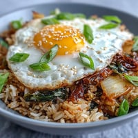 Vibrant kimchi cabbage fried rice topped with a sunny-side-up egg.